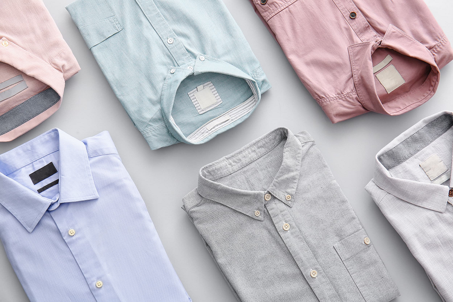 A selection of neatly folded button-up shirts on a light grey background.